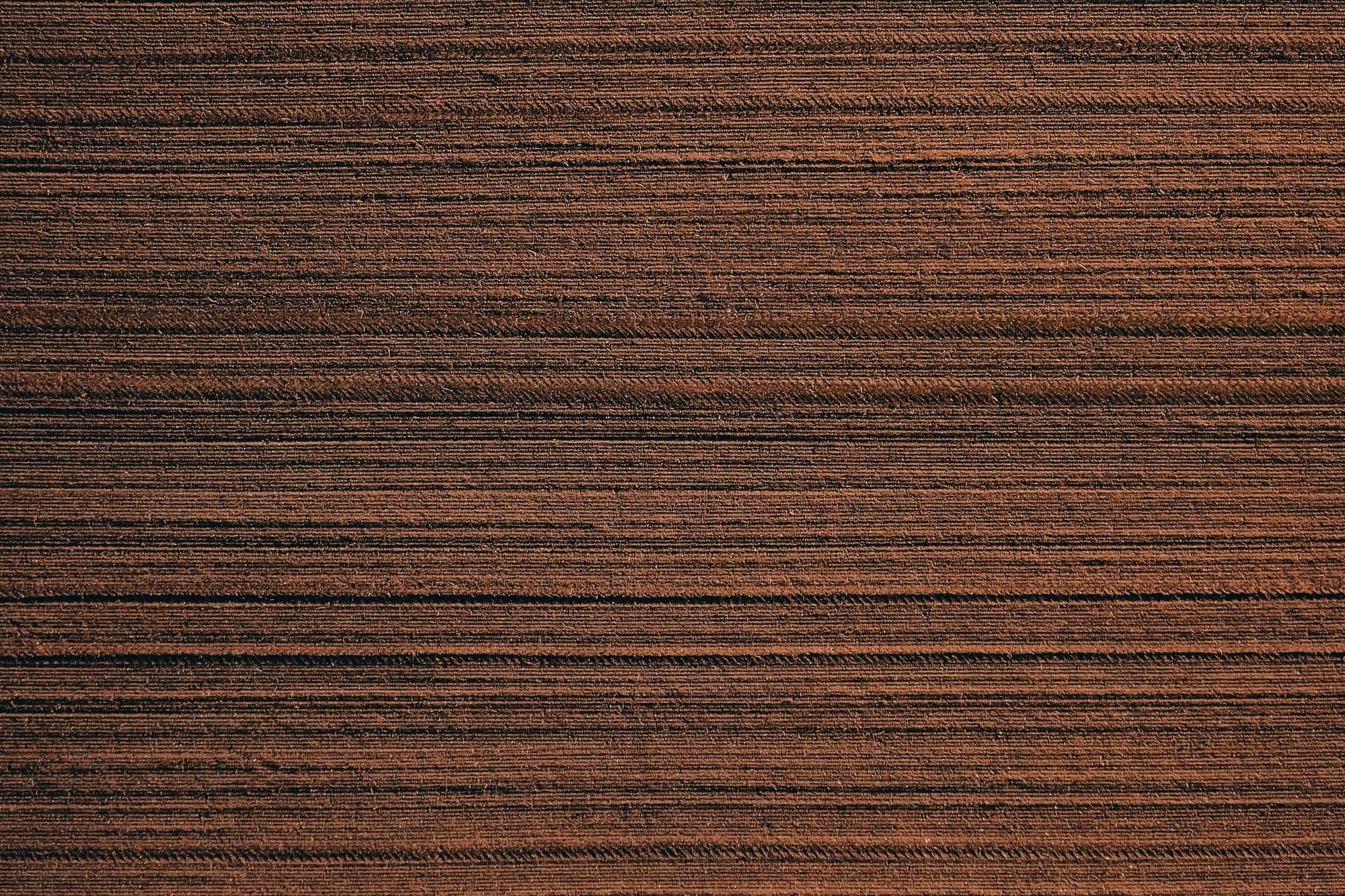 Dark walnut veneer surface with straight, parallel grain (quarter-cut look), close-up.
