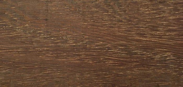 Azobé lumber surface: dark red-brown, coarse-textured wood, close-up.