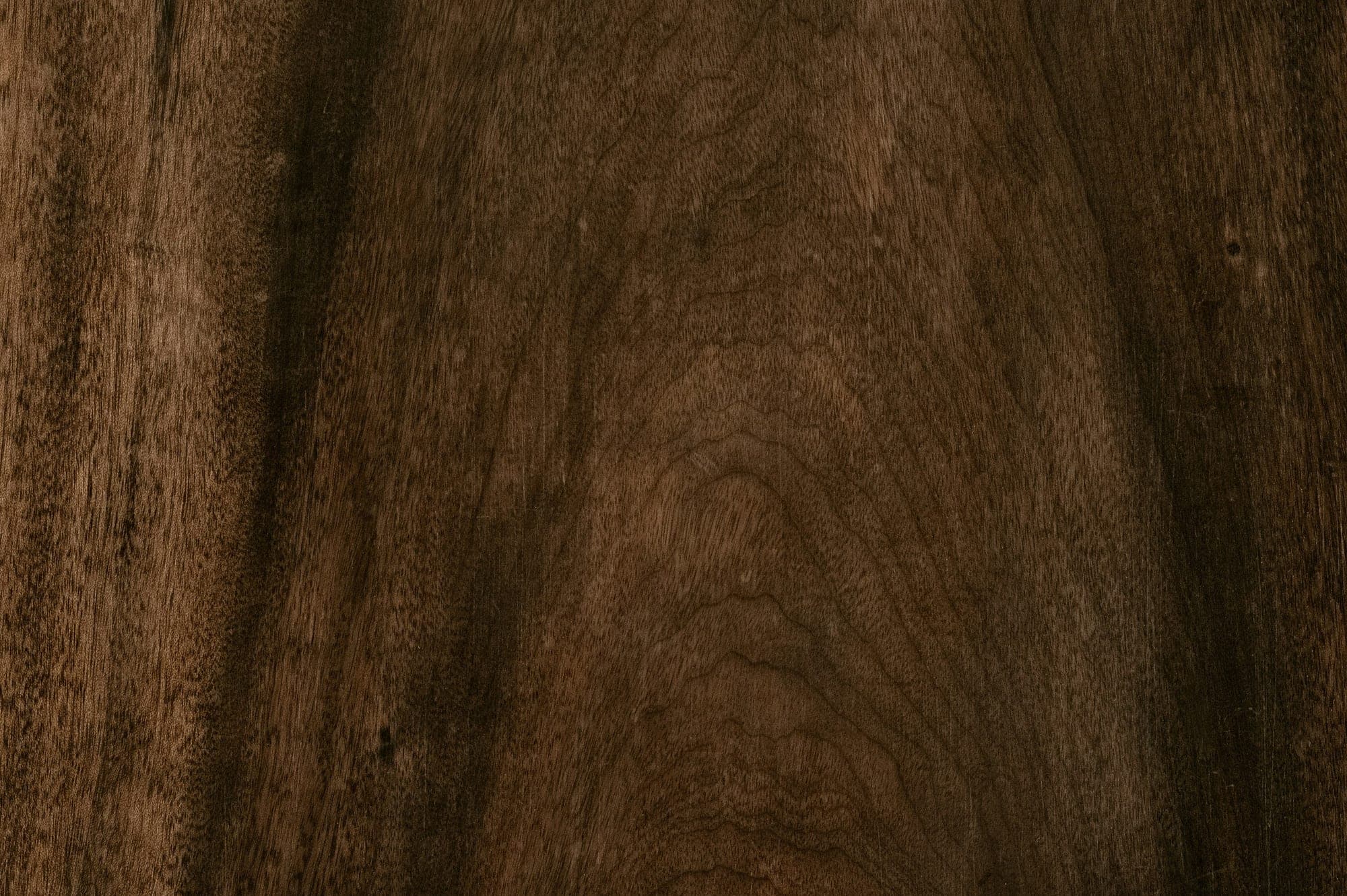 Walnut veneer surface with lively figure and warm brown tones, close-up.