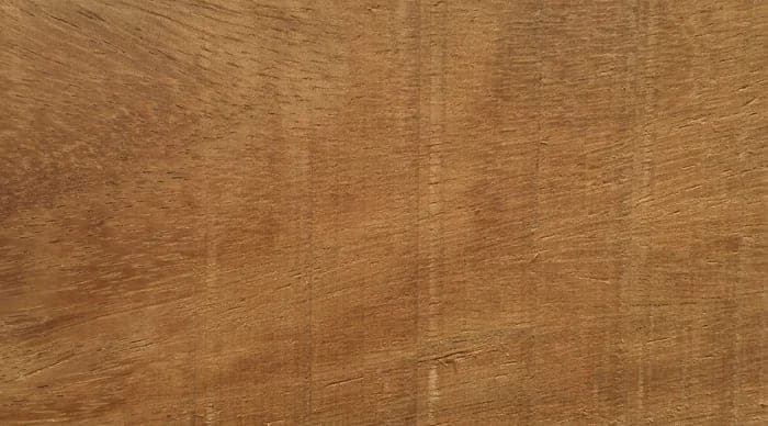 Dabéma lumber surface: golden-brown, coarse-textured wood, close-up.