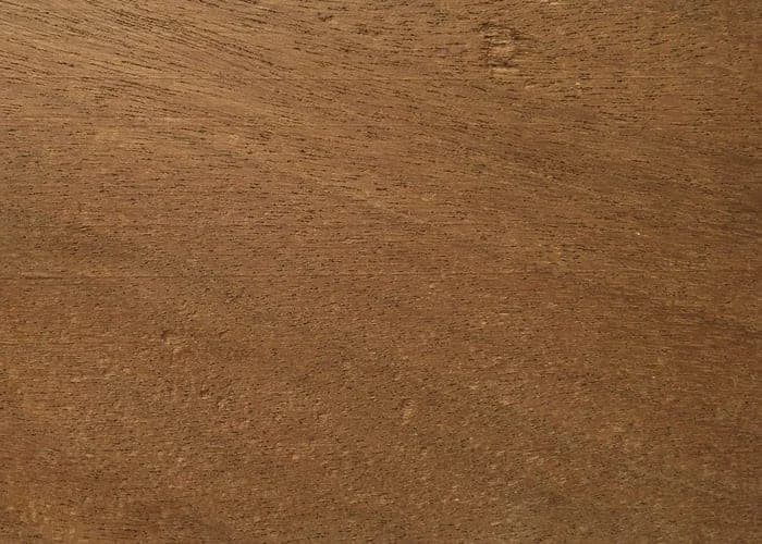 Dibetou (African walnut) lumber surface: walnut-toned brown wood, close-up.