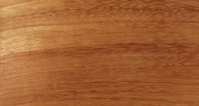 Doussié lumber surface: honey to red-brown wood, close-up.