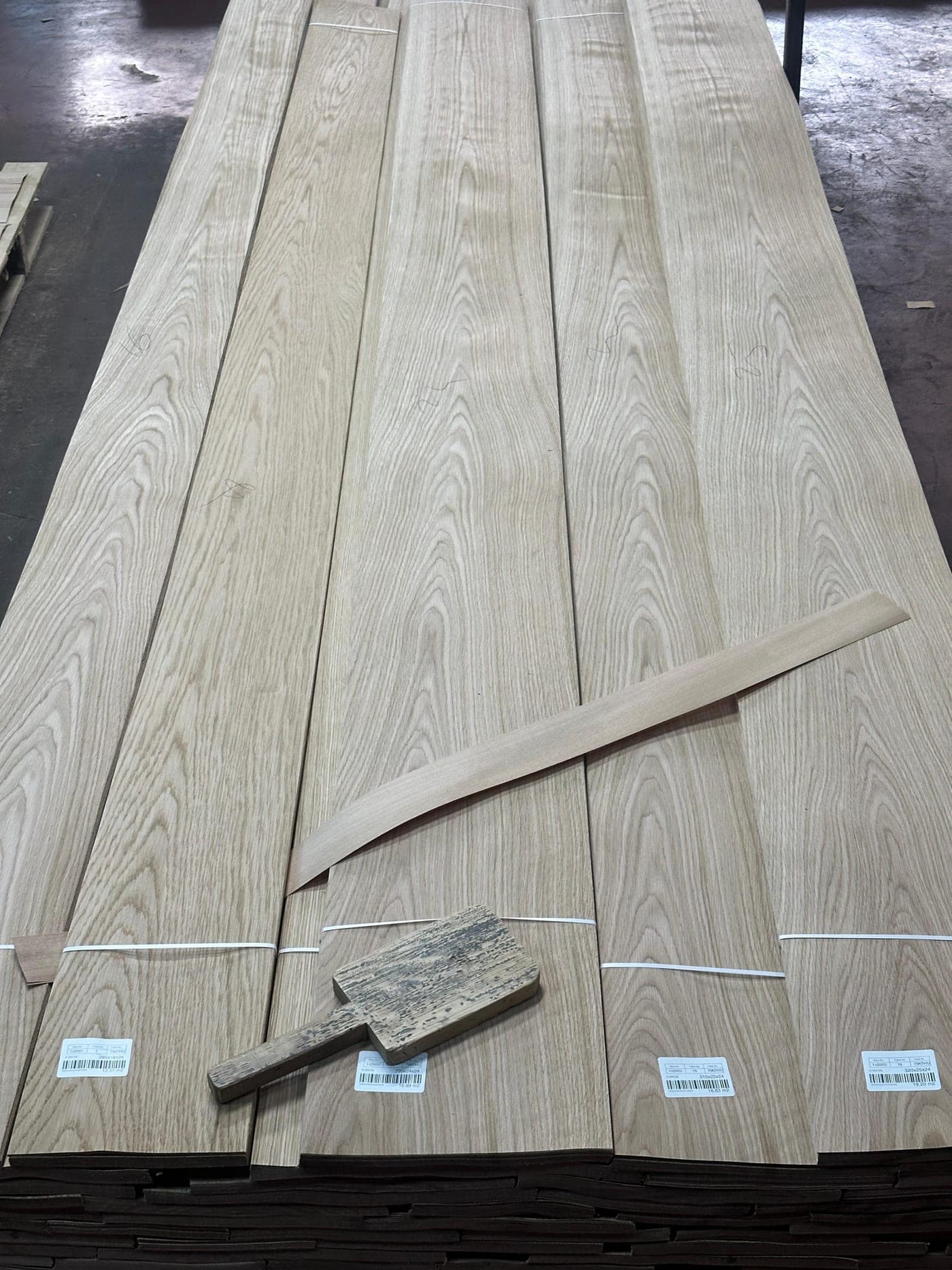 Labelled bundles of natural wood veneer, stacked.