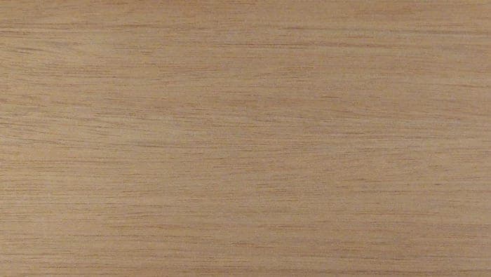 Okoumé lumber surface: pinkish light brown, fine-textured wood, close-up.