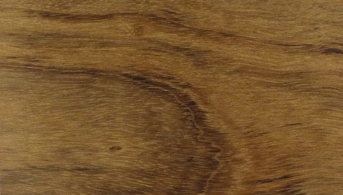 Ovèngkol lumber surface: olive and golden-brown wood with dark stripes, close-up.