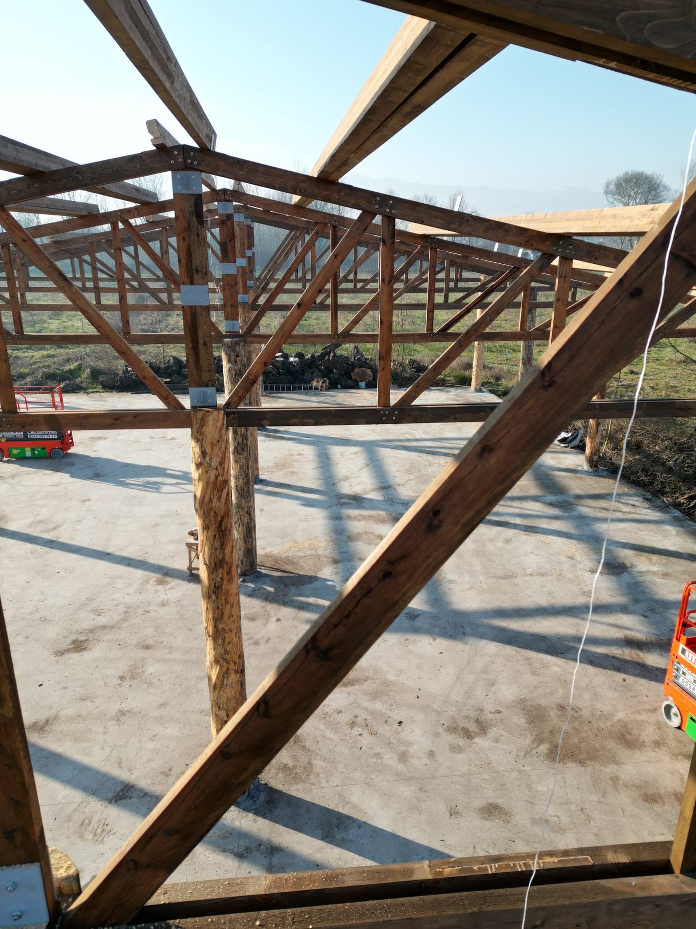 Nativu timber truss and beam frame on round timber posts over a concrete slab.